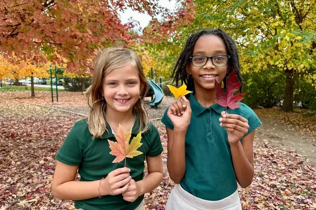 two students holding a leaf