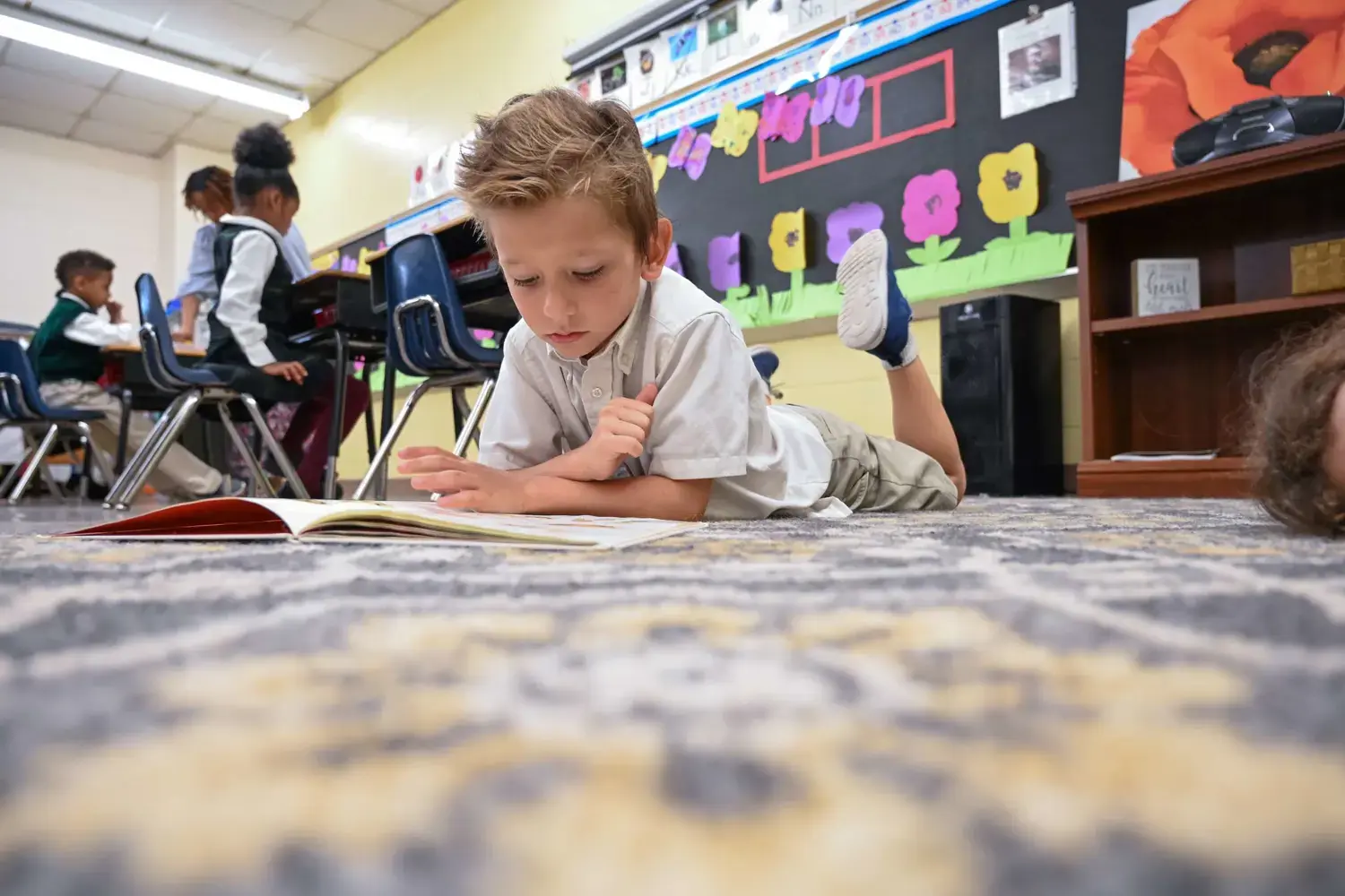 Kindergarten boy reading on the rug during independent learning time.