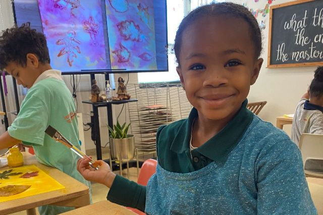 PreK student smiling while painting