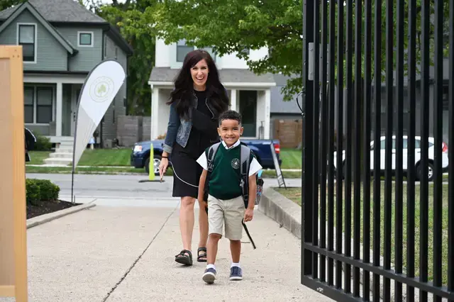 early education student walking through gates with parent behind them